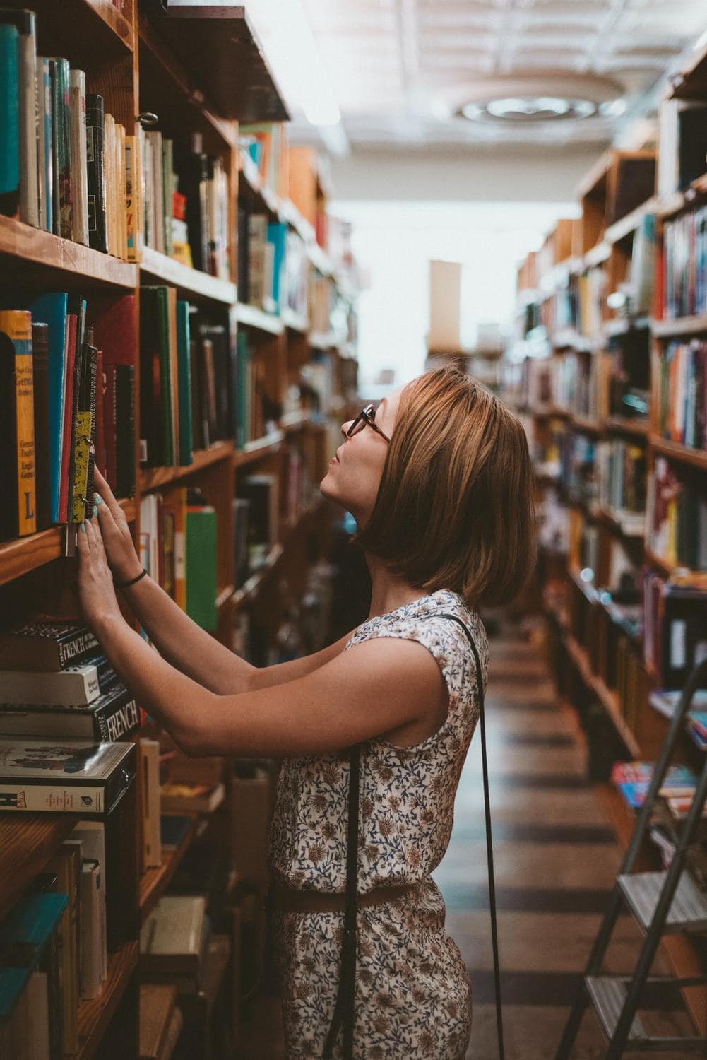 Junge Frau zieht ein Buch aus einem Regal