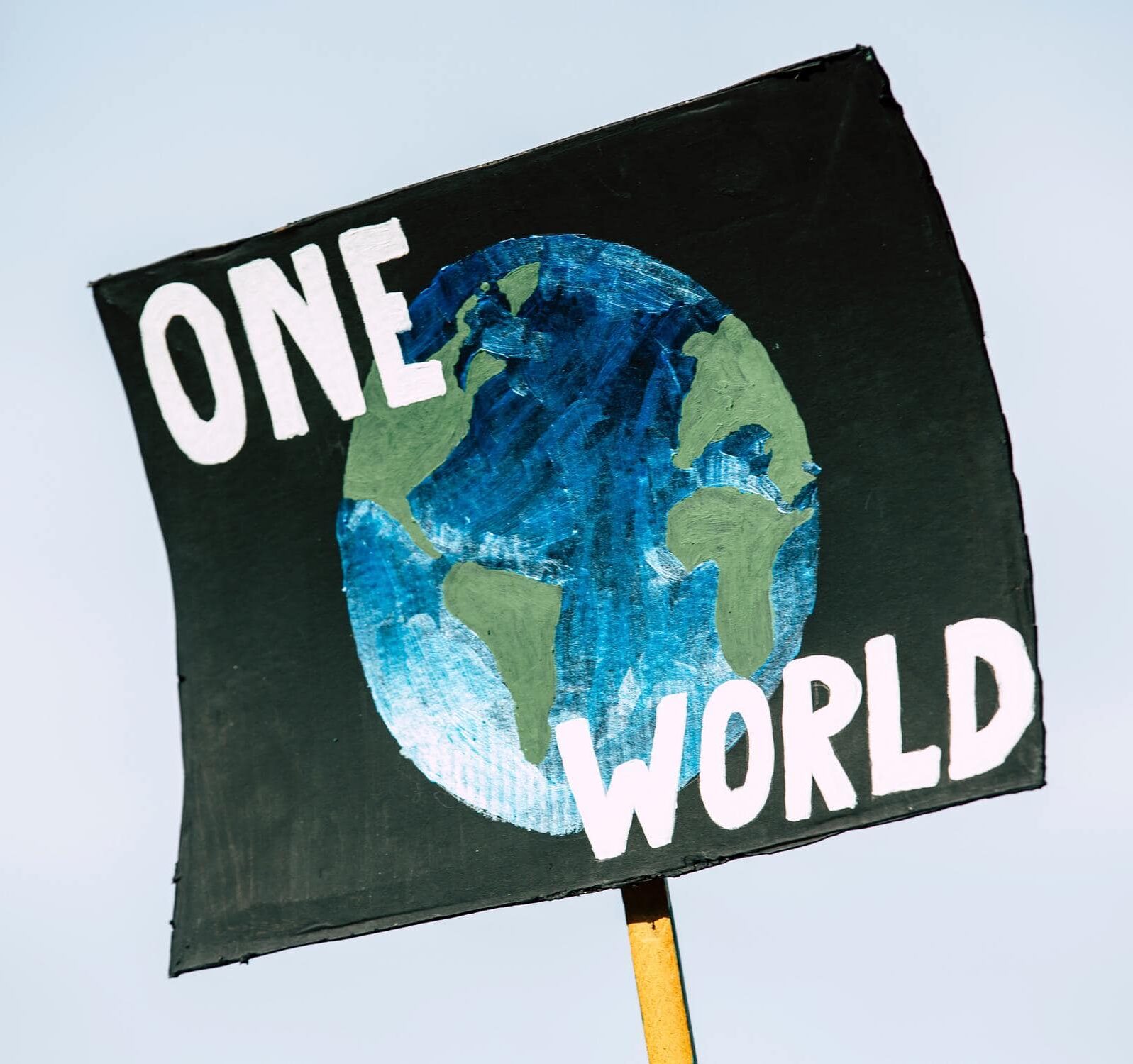 Schwarzes Plakat mit dem Planeten Erde und dem Schriftzug "One World" darauf.