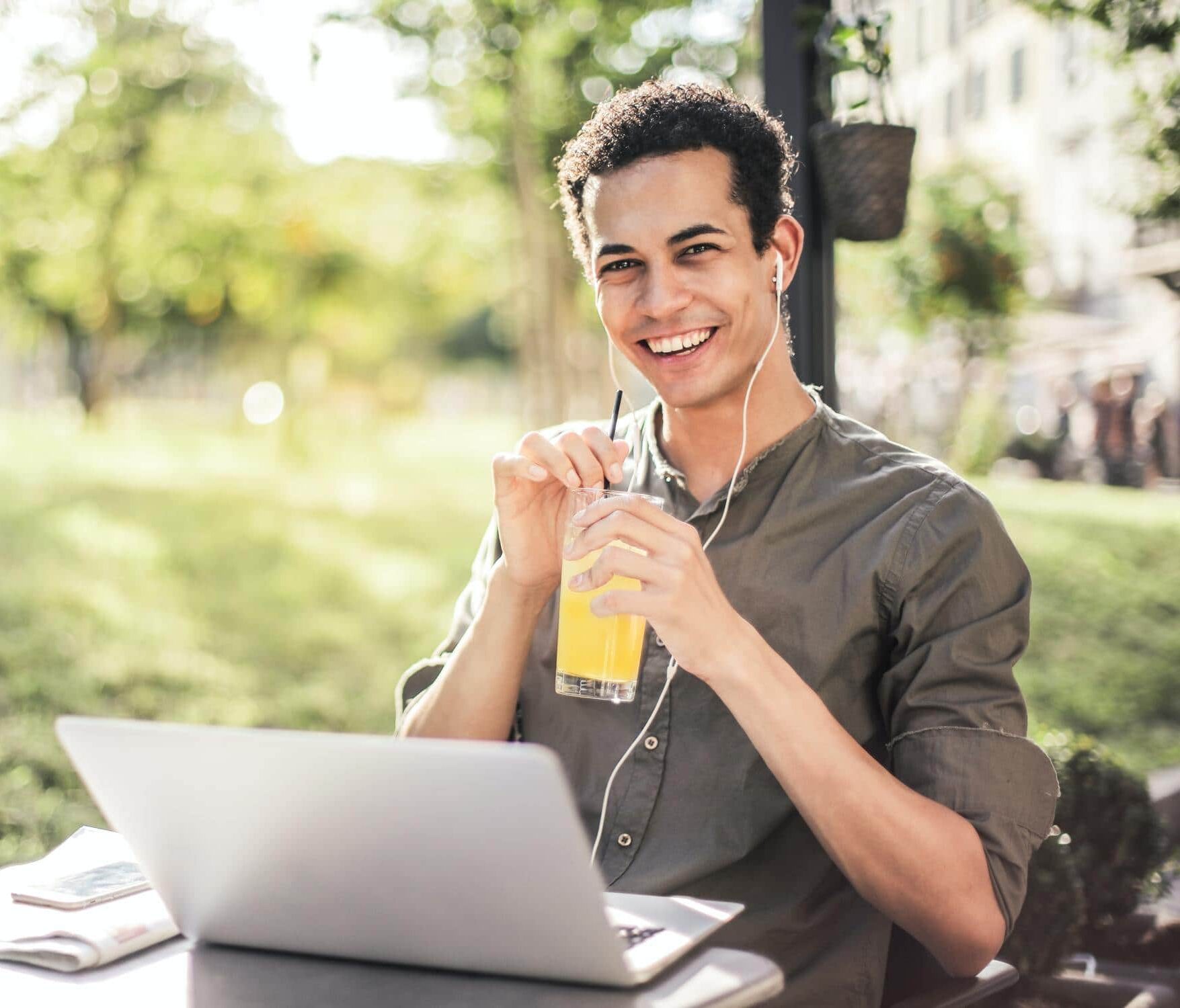 Junger Student sitzt im Freien und lächelt, weil ihm sein Technik-Studium Spaß macht