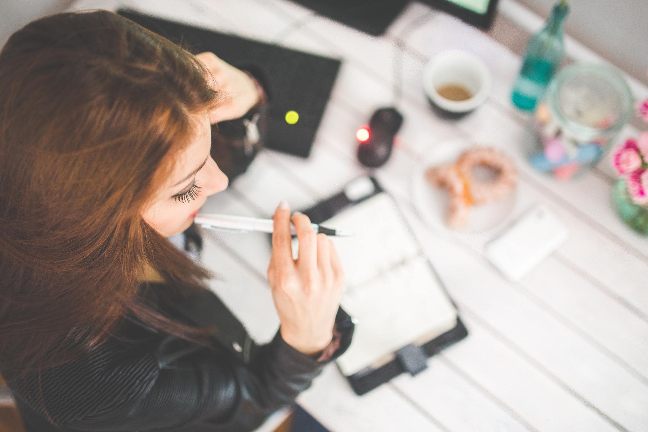 Junges Mädchen sitzt an Tisch und überlegt, ob sie nach der HTL arbeiten oder studieren soll