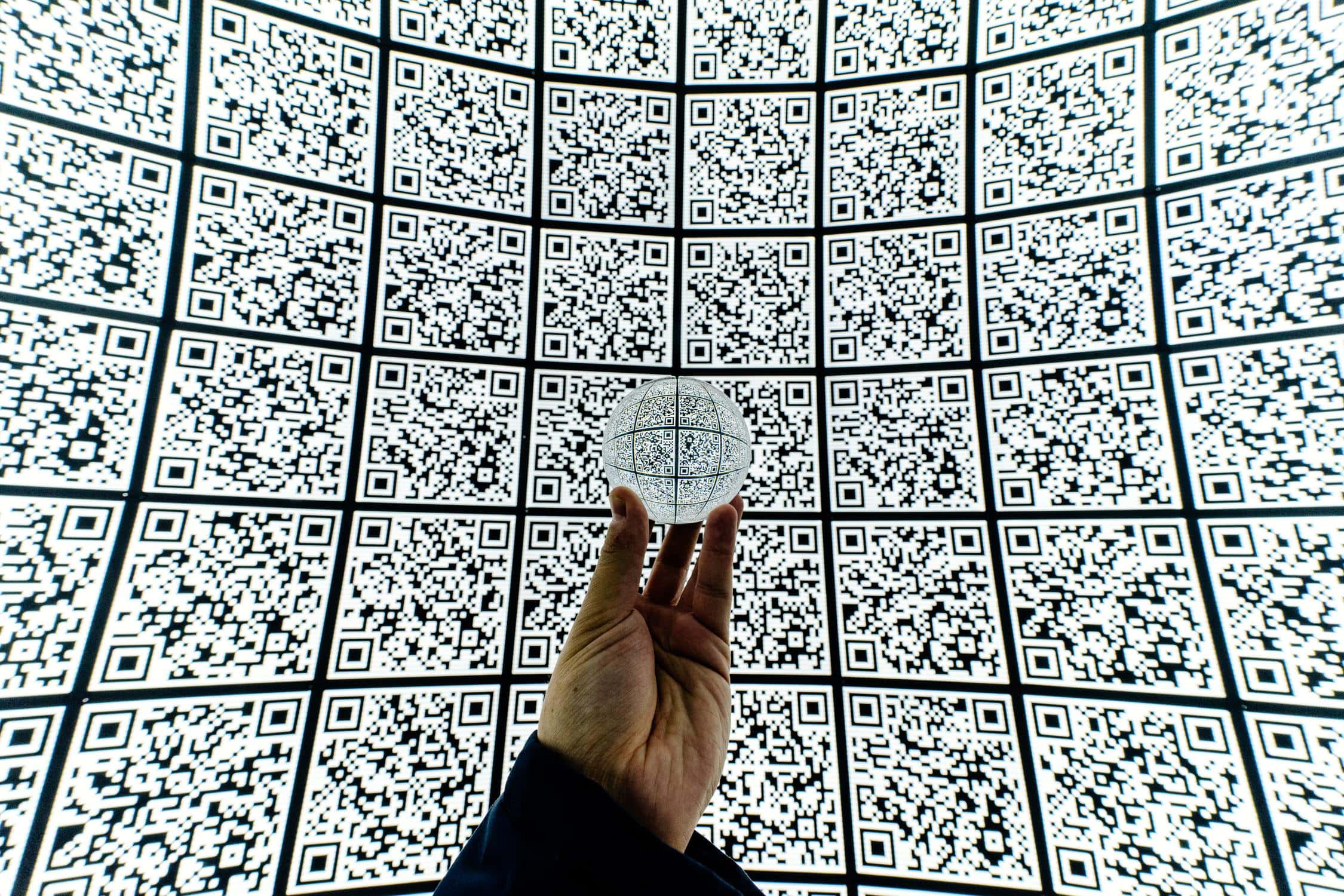 Hand vor vielen QR-Codes, die den ganzen Raum ausfüllen