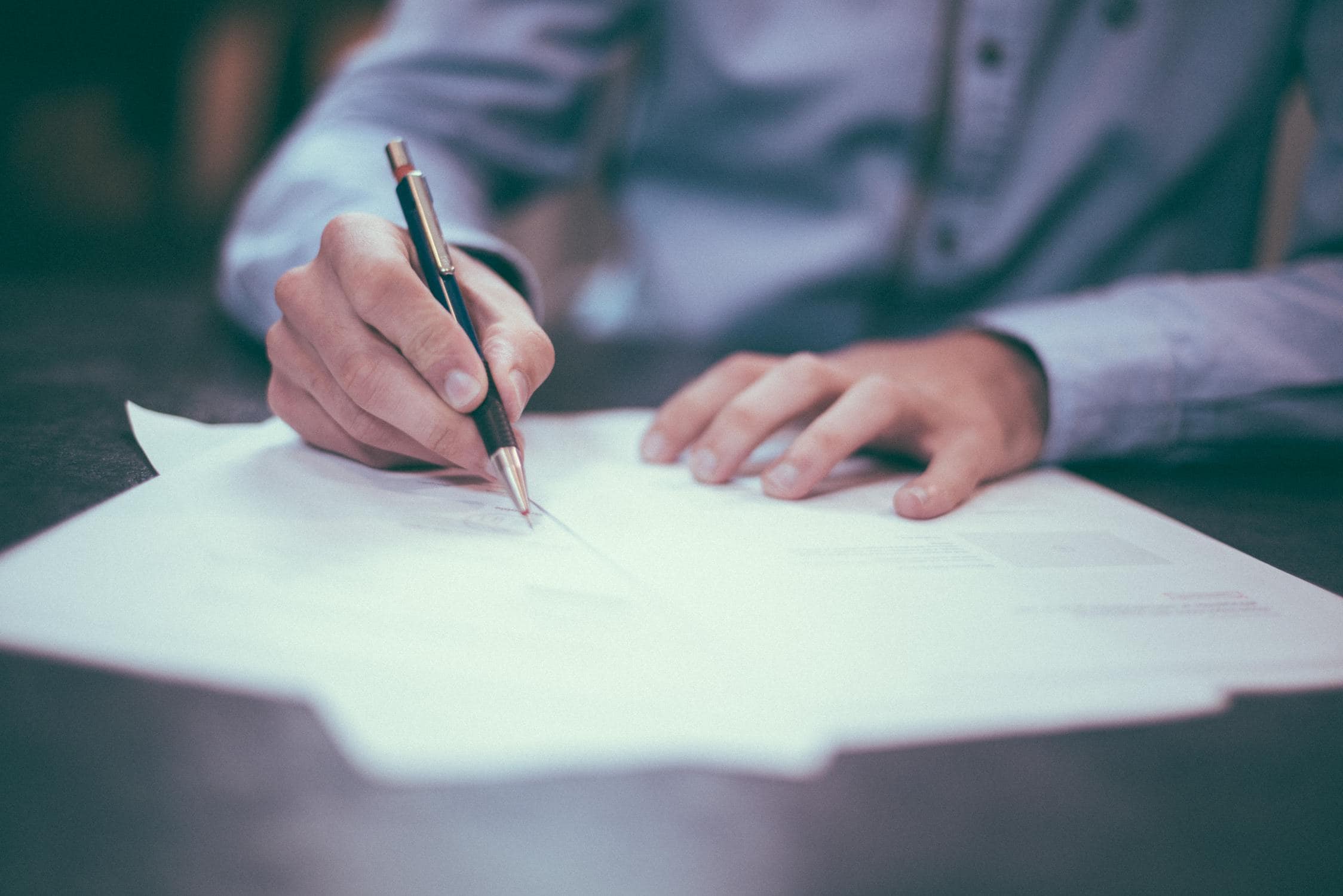 Hände, die einen Stift in der Hand halten und auf Papier schreiben