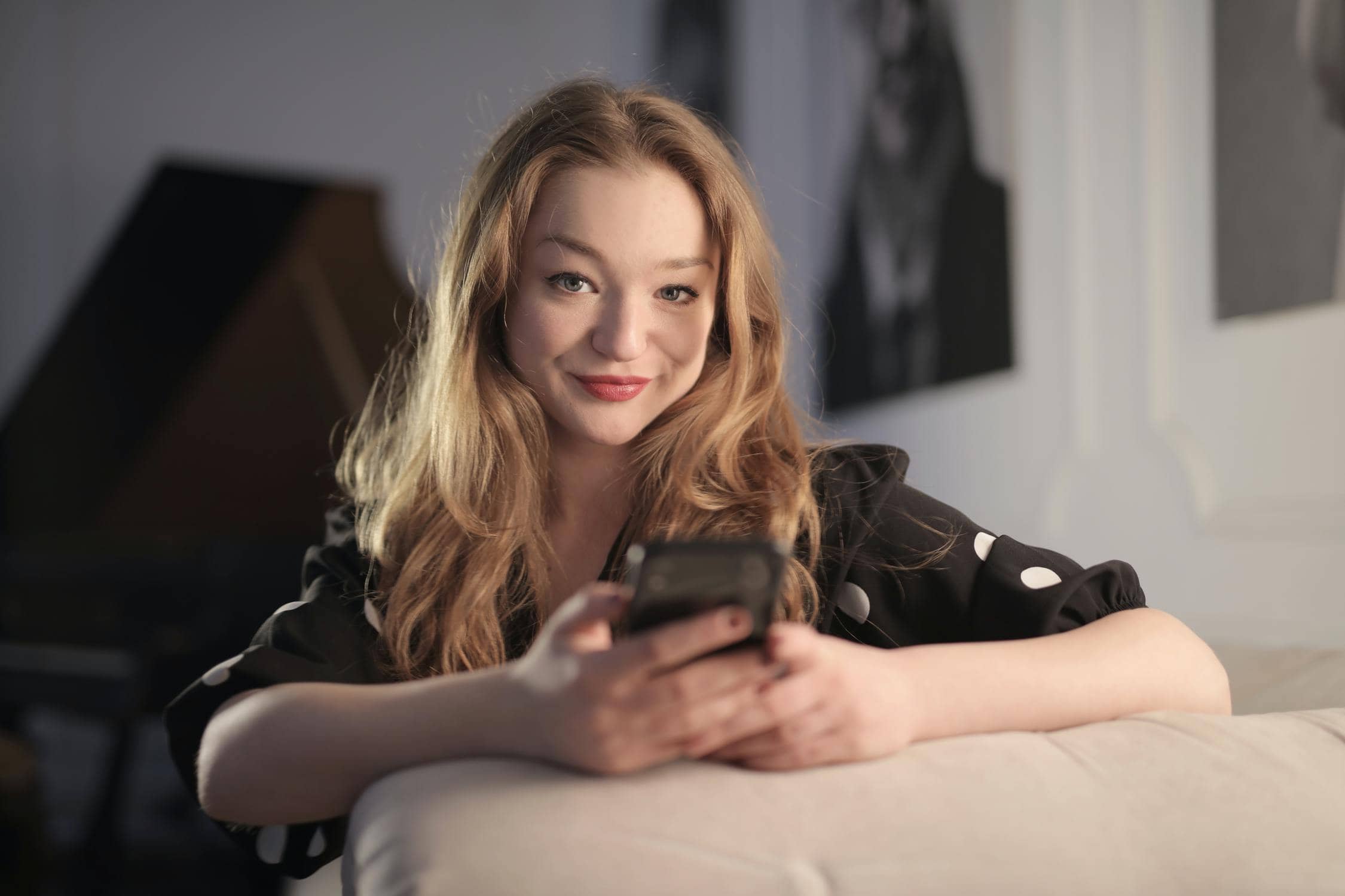 Mädchen lächelt sicher mit Handy in die Kamera, weil sie ein sicheres Passwort hat