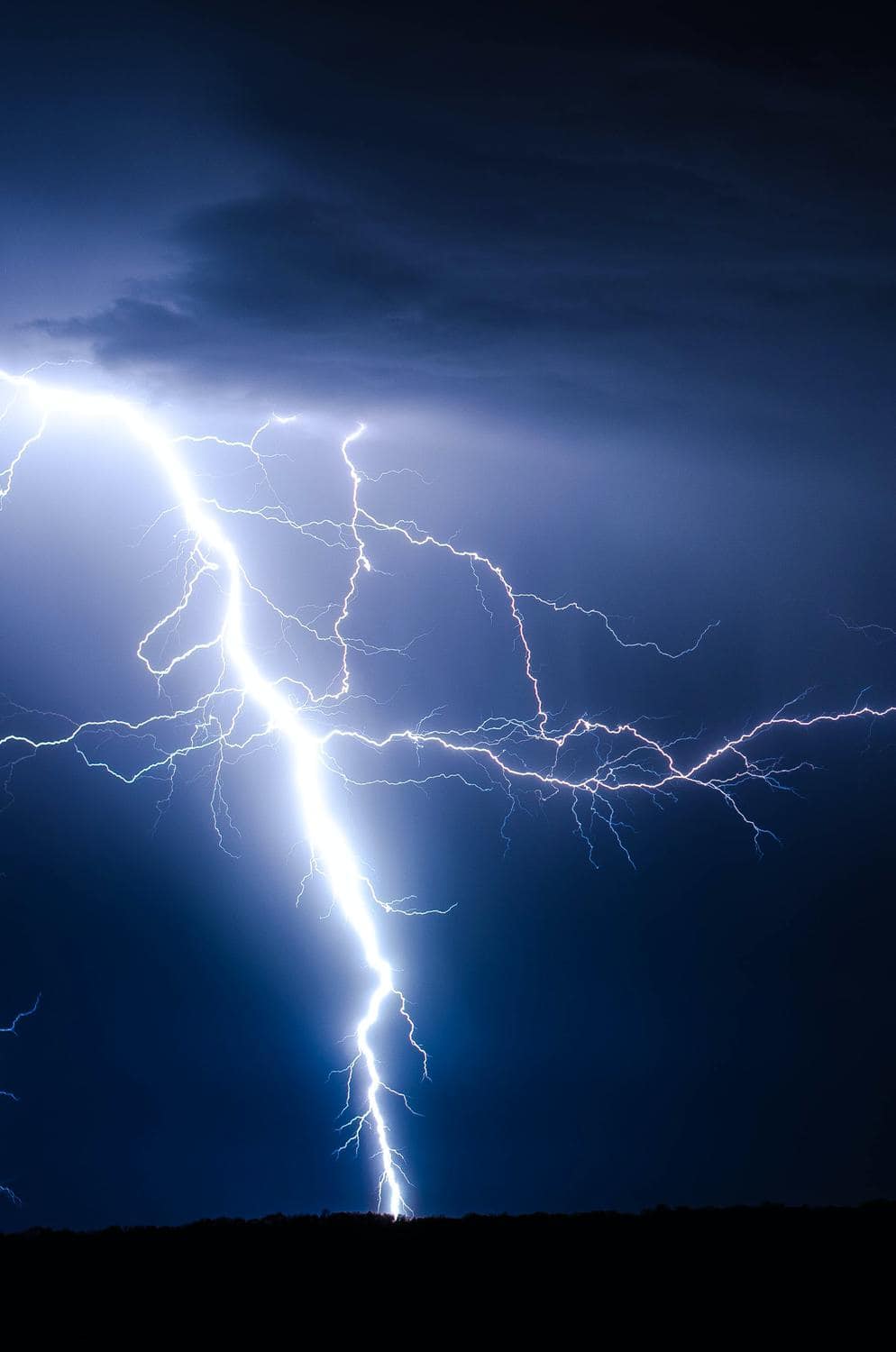 Blitz schlägt bei Gewitter auf dunkler Fläche ein