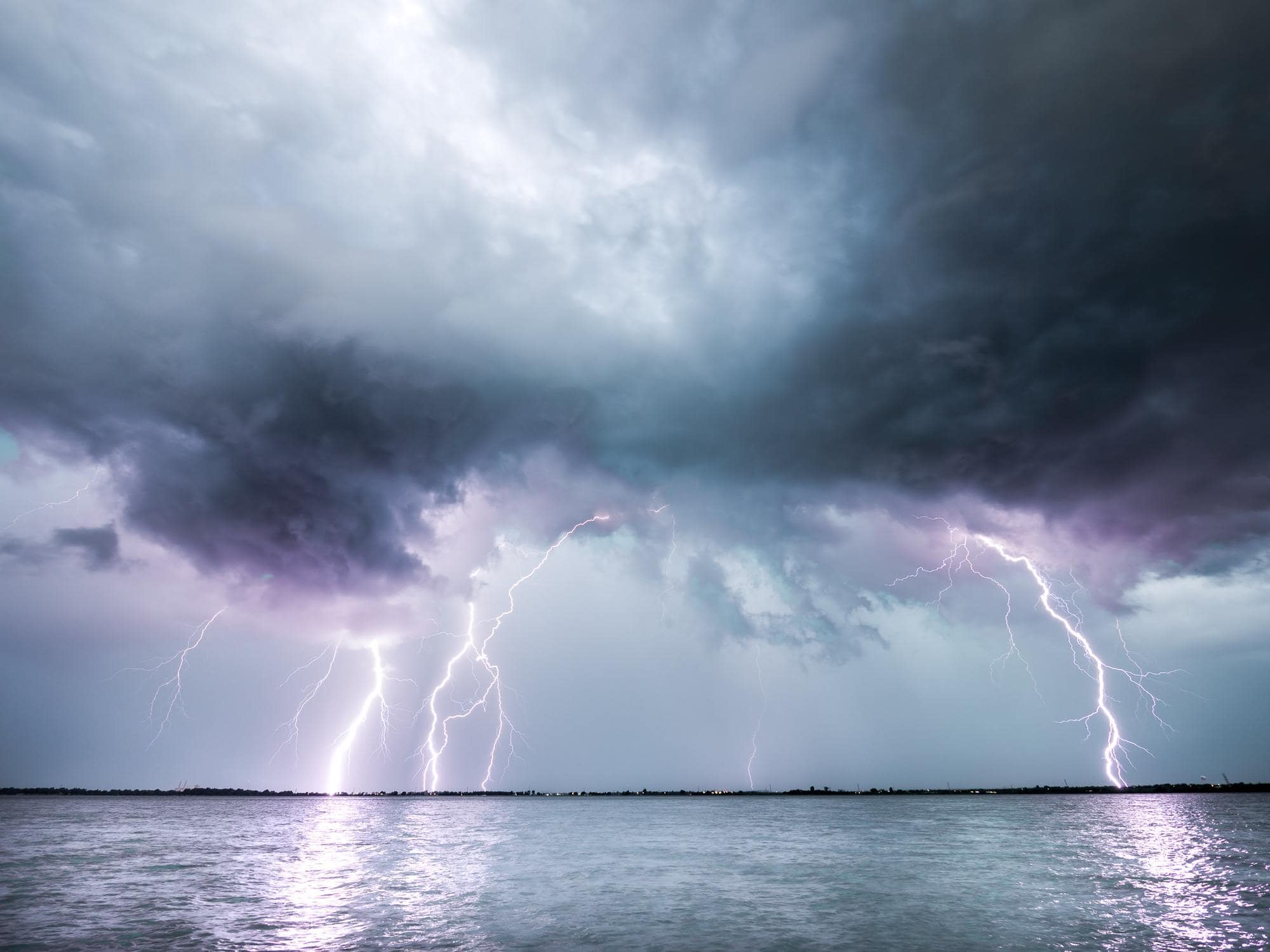 Gewitter über Wasser mit einschlagenden Blitzen