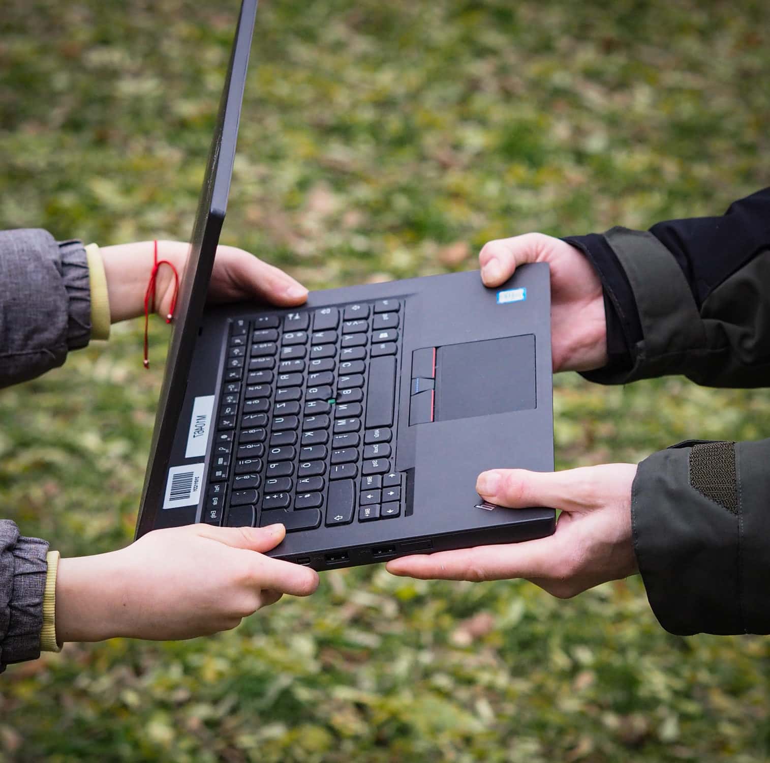 Ein Laptop wird von vier Händen gehalten, um eine Geräteübergabe bei PCs für alle darzustellen