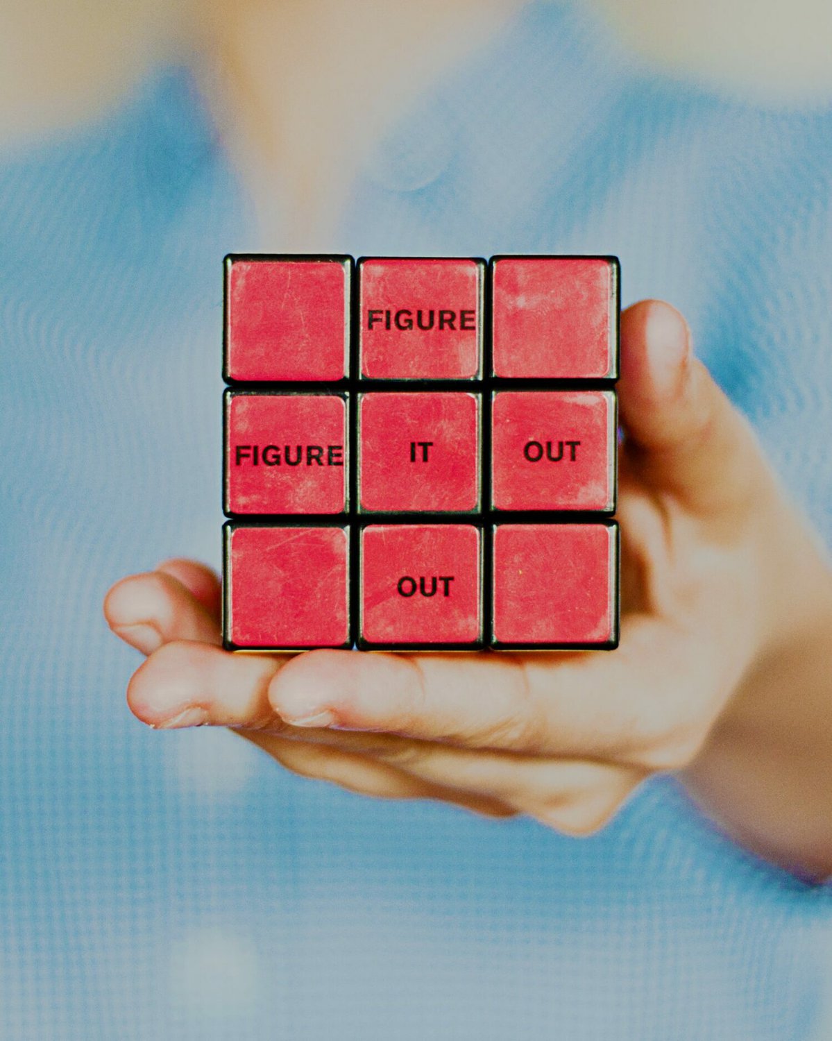 Vorderseite eines roten Rubikwürfels in einer Hand mit Aufdruck "figure it out"
