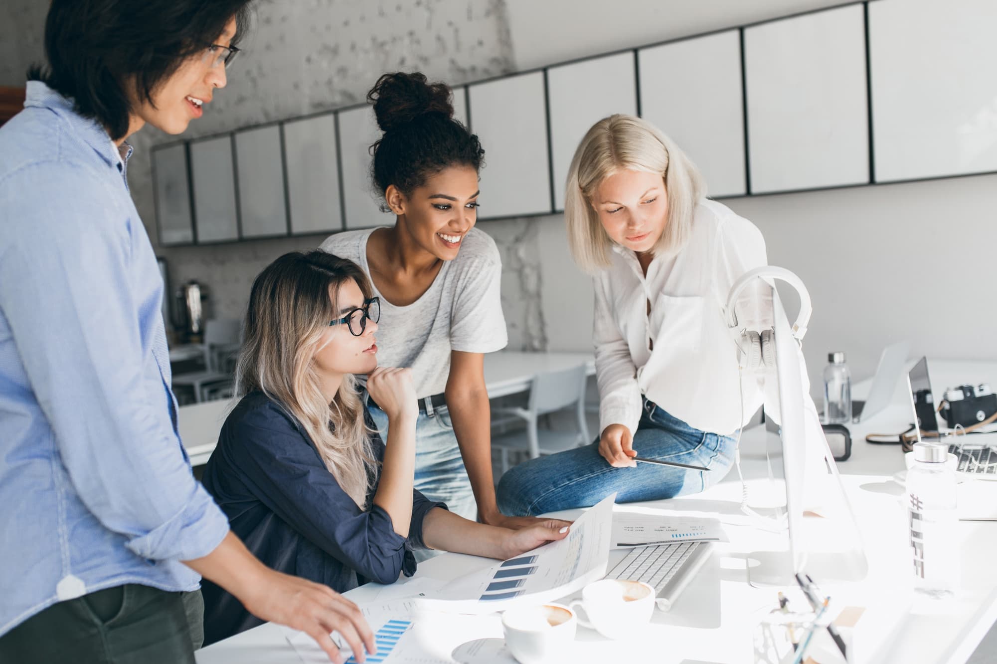 Vier Frauen gemeinsam vor einem Schreibtisch. Sie schauen gemeinsam auf einen Computerbildschirm.