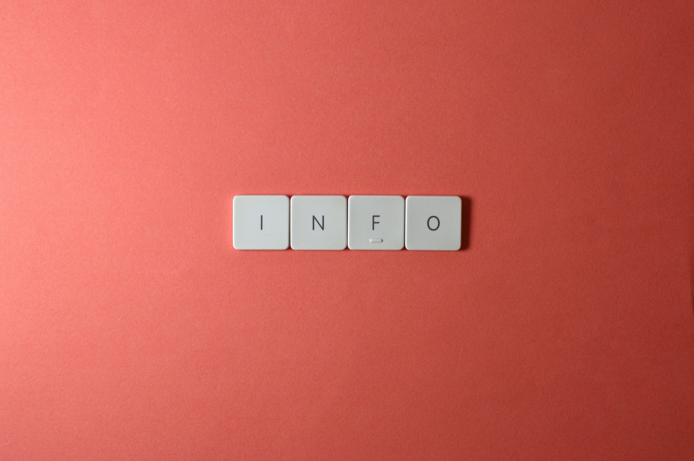 Das Wort "Info" in einzelnen Buchstaben auf einer weißen Computertastatur vor rotem Hintergrund.
