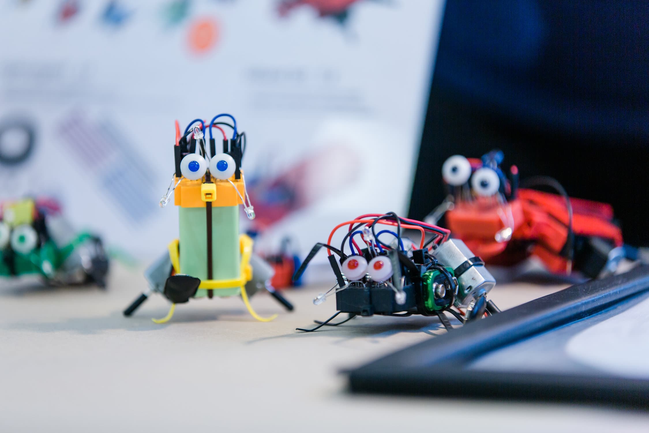 3 kleine bunte Roboter mit aufgeklebten Augen, die auf der Maker Faire Vienna entstanden sind