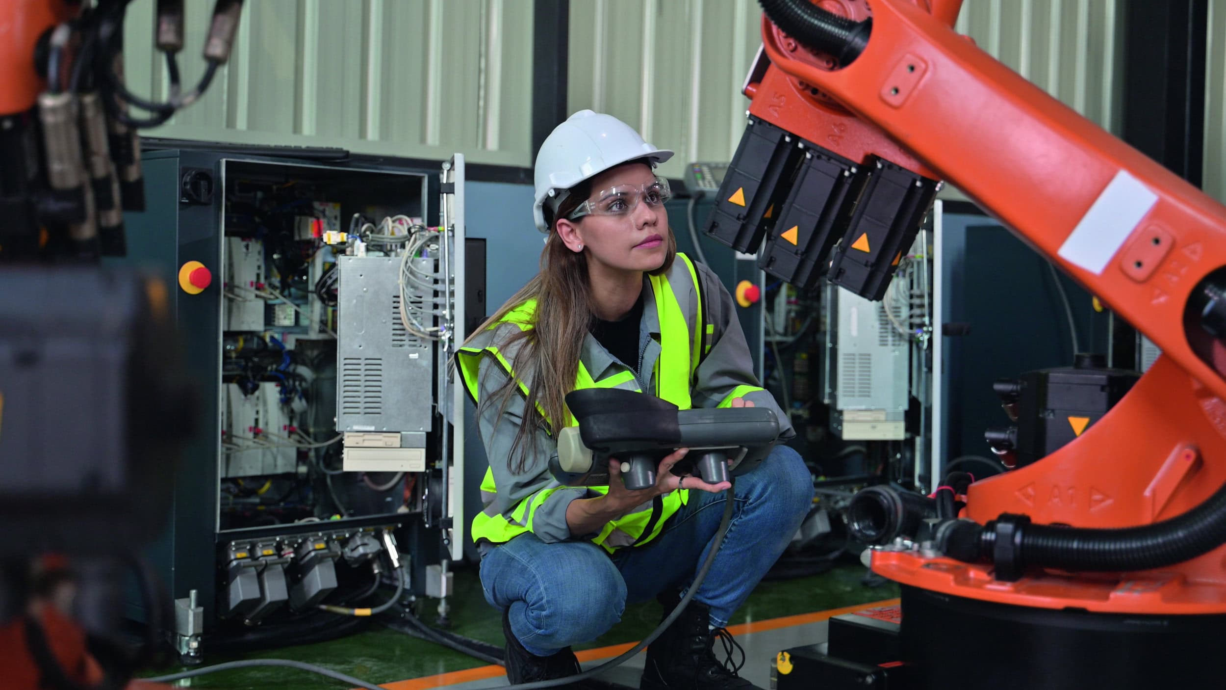 Wartungsingeneurin arbeitet mit Roboterarm.