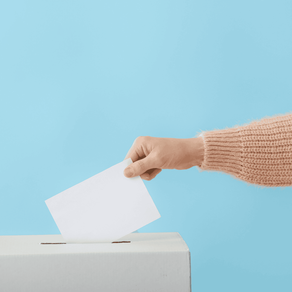 Hand wirft Wahlkarte in weiße Box