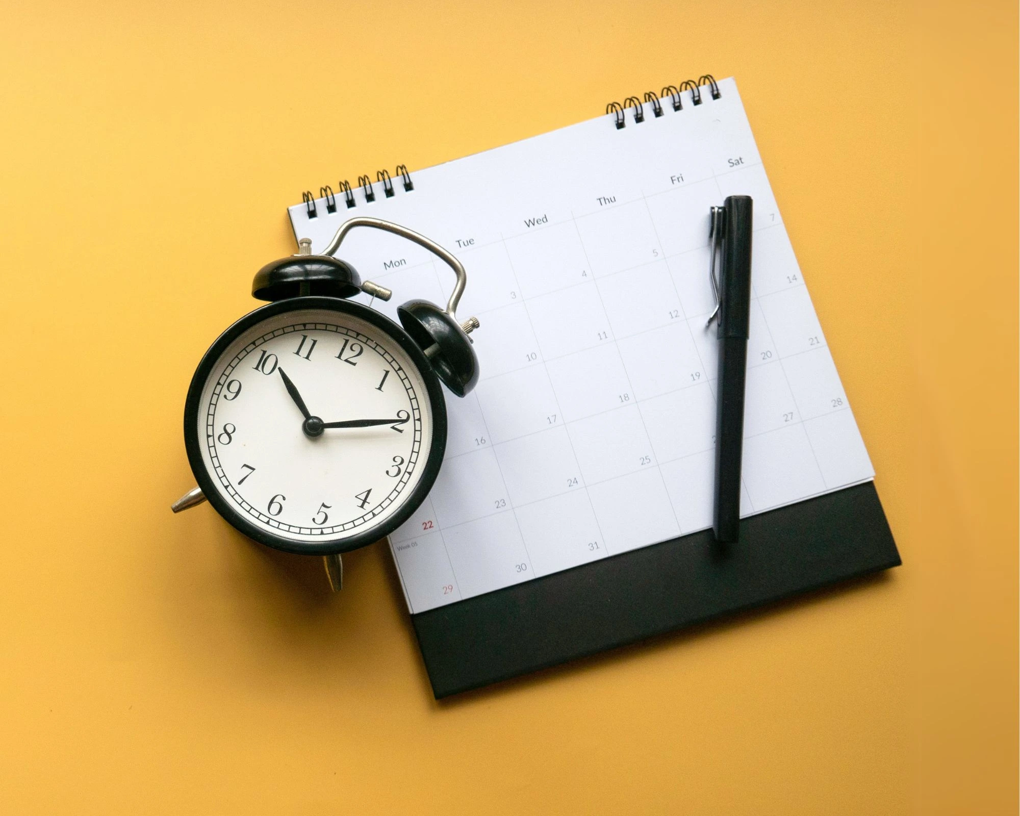 Ein Wecker und Stift auf einem Kalender
