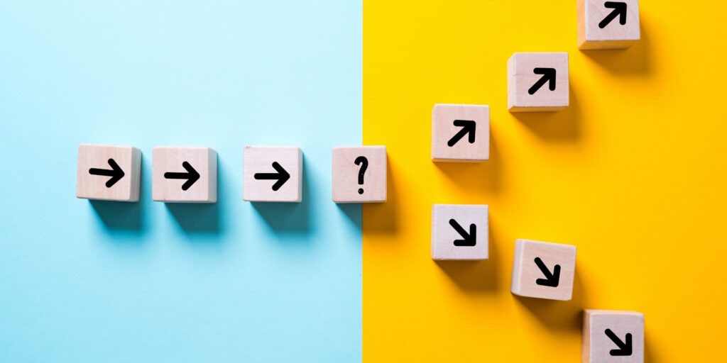 Kleine Holzblöcke mit Pfeilen, die in unterschiedliche Richtungen zeigen, um die Entscheidungsfindung bei der Jobsuche zu symbolisieren