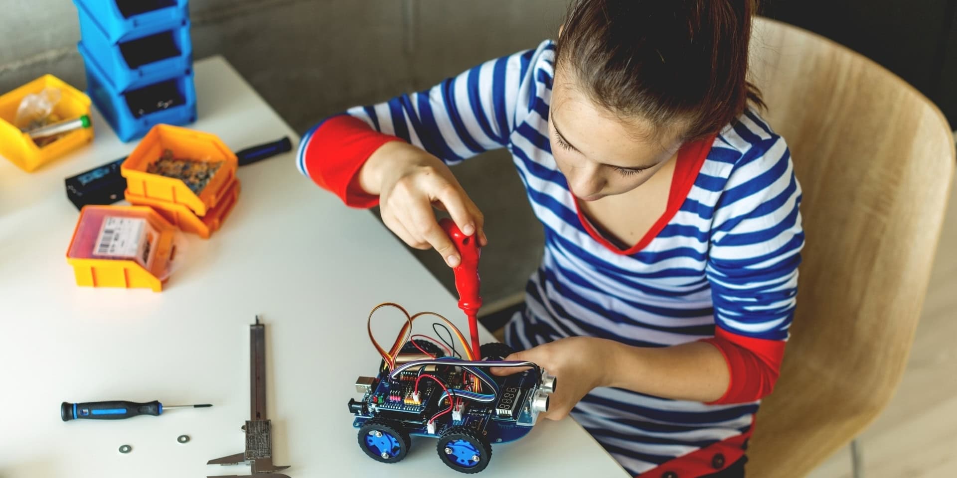 Mädchen schraubt an einem Roboter