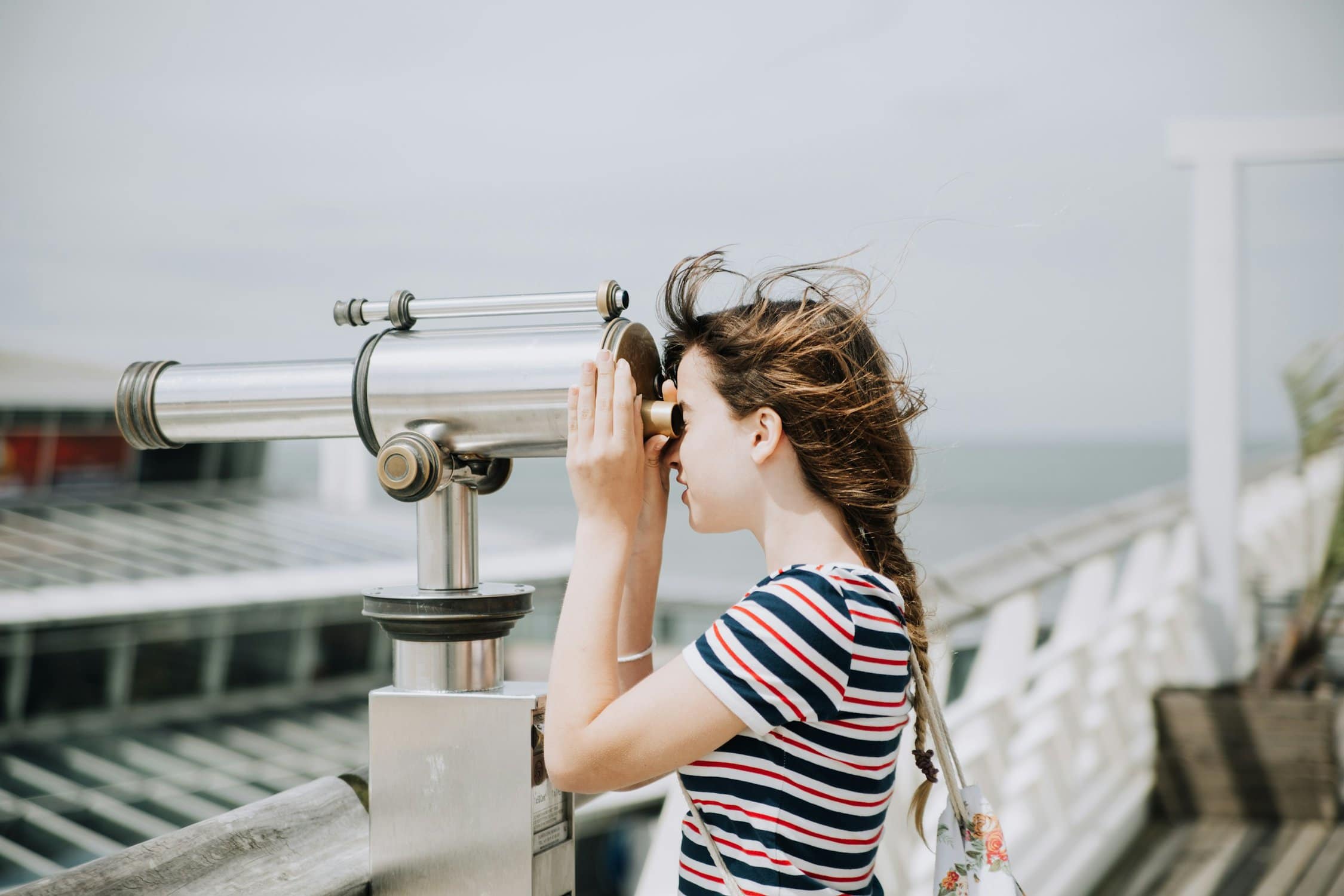 Mädchen schaut auf einer Plattform durch ein Fernglas.