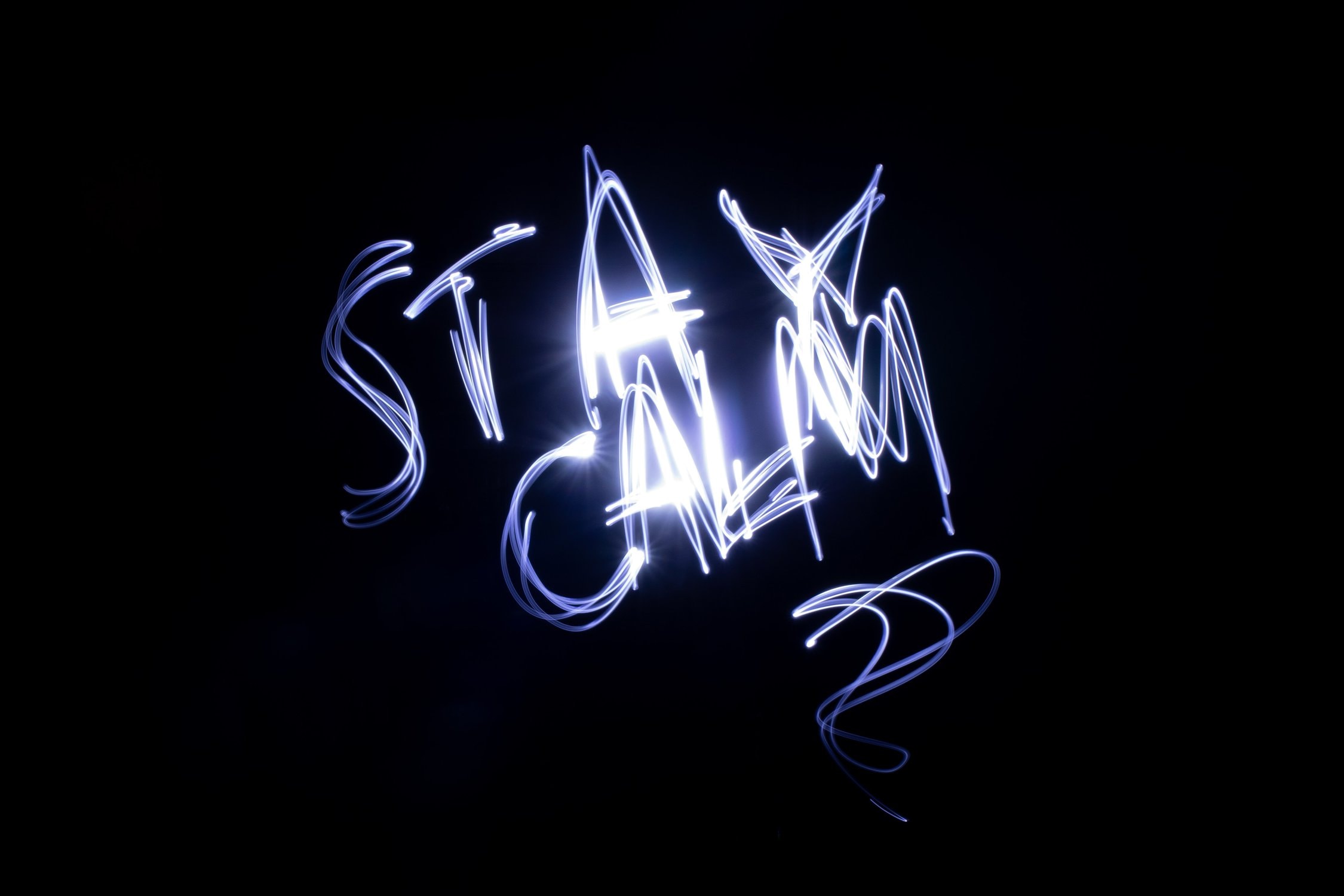 Leuchtende Schrift mit dem Text "Stay Calm" in der Dunkelheit