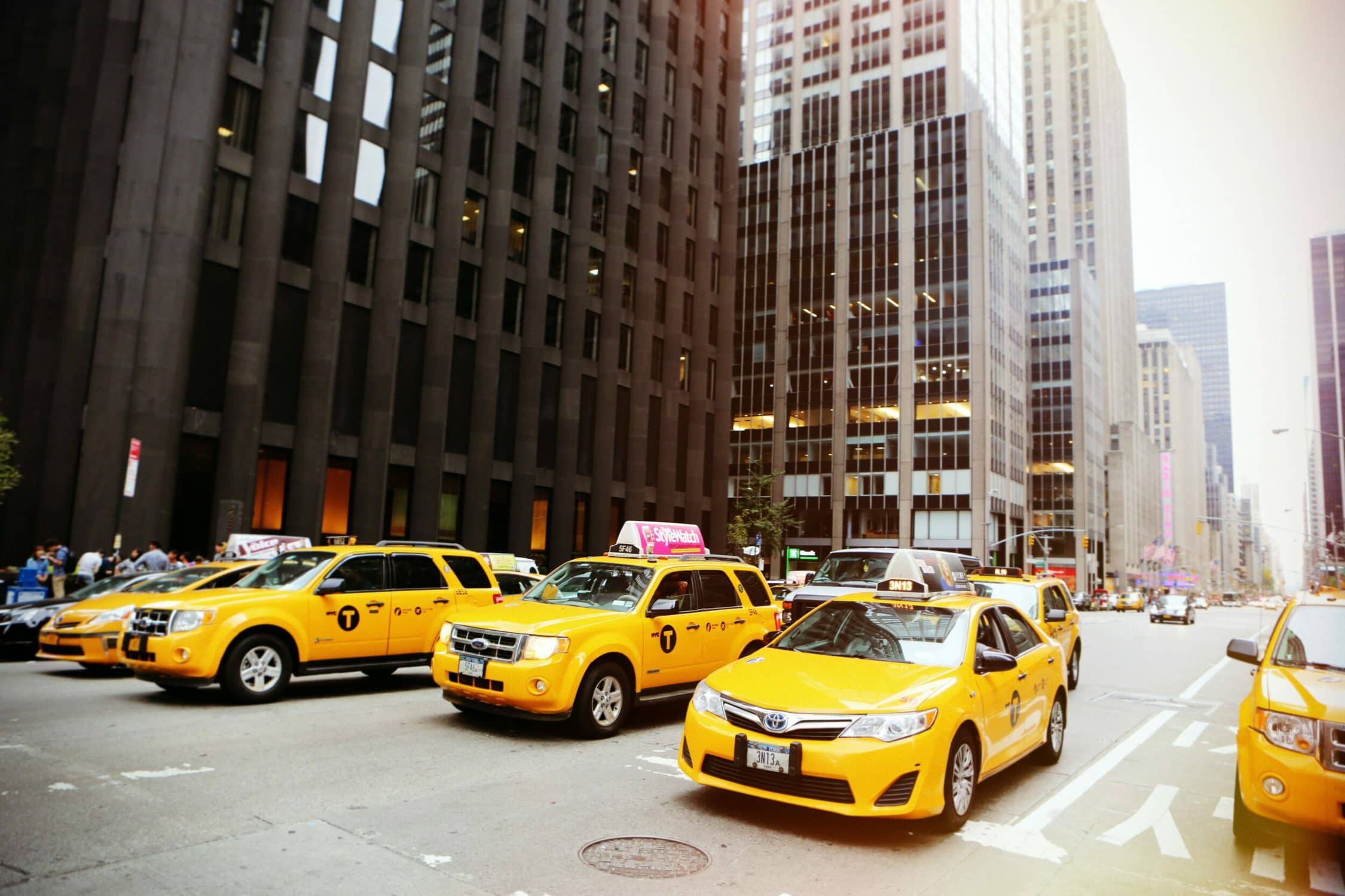 Gelbe Taxis stehen vor Wolkenkratzern auf der Straße.