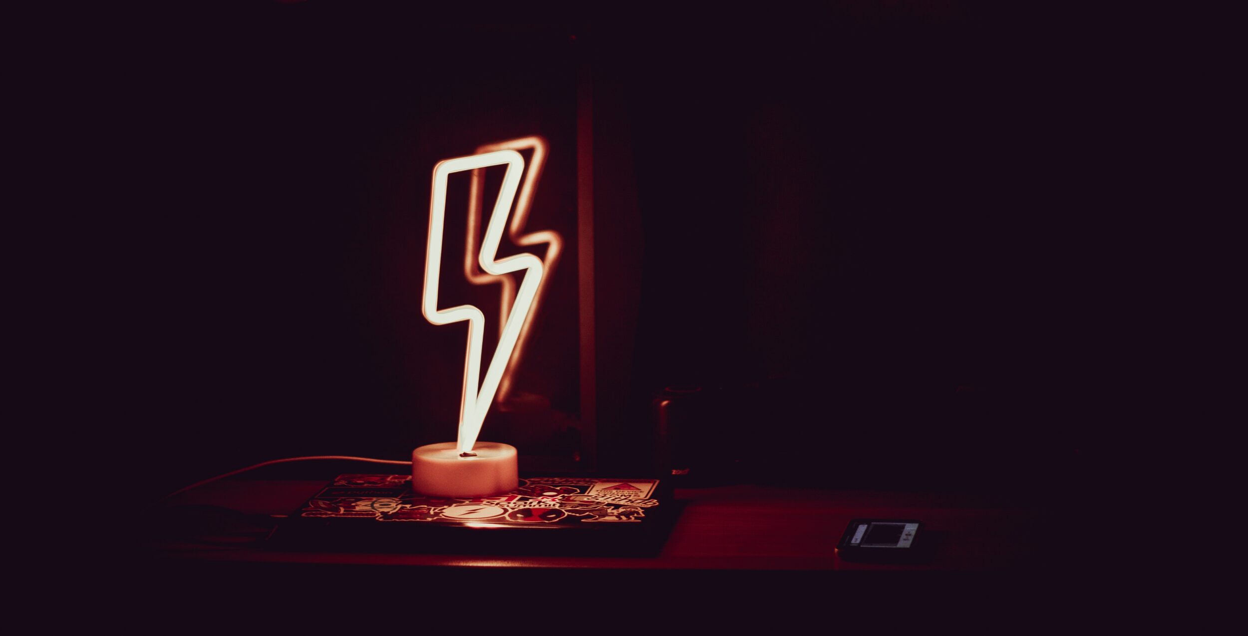 Eine leuchtende Lampe in Form eines Blitzes steht auf einem Tisch im Dunkeln.
