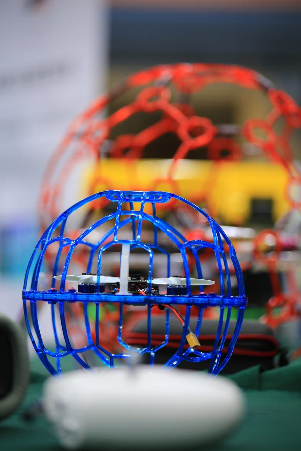 Eine kleine Flugdrohne in einem blauen, runden Käfig, die als Drohnenball beim Drohnen-Fußball eingesetzt wird.